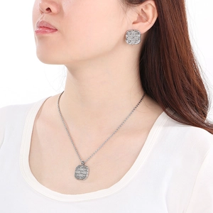 Close-up of silver-toned textured square pendant necklace and matching stud earrings on a model
