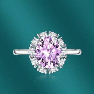 Macro view of oval pink gemstone ring with white zircon halo and silver band detail