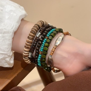 Detail of bohemian stackable beaded bracelets featuring wood beads and ethnic charms
