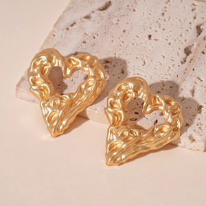Detailed close-up of golden heart earrings with unique lava texture and molten metal finish
