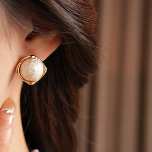 Close-up of a model wearing vintage gold-plated round earrings with cotton pearl inlay
