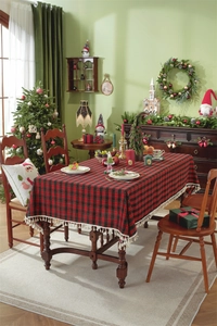 Detail of red and black plaid Christmas tablecloth featuring elegant beige tassel fringe