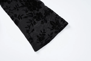 Détail de la manche en mesh noir avec motifs de roses floqués et poignets texturés