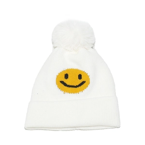 Close-up of white ribbed knit beanie featuring a yellow smiley face and faux fur pompom