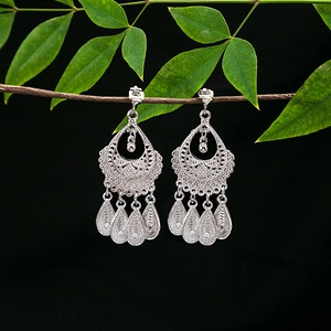 Detailed view of silver ethnic earrings with five tassels on green leaves background