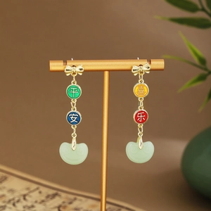 Detail of Chinese style earrings with gold tassels and green Ruyi jade-like pendants