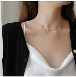 Close-up of a gold titanium necklace with small rectangular pendants on a female model