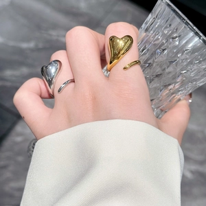 Detailed view of intertwined 18k gold and silver heart rings worn on a model's hand