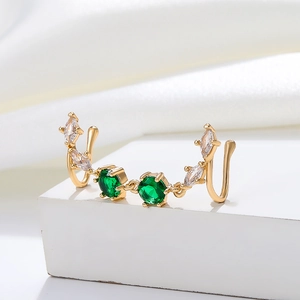 Macro shot of gold-plated U-shaped faux nose ring with green gems and white zircons