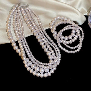 Detail shot of multi-layer pale pink pearl necklace set on beige and black fabric