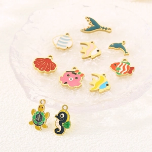 Detailed view of ten colorful enamel marine animal pendants on a glass plate for DIY jewelry