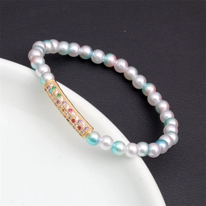 Close-up of beaded bracelet with colorful zircon curved bar on a white ceramic plate