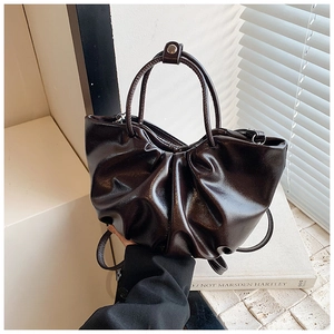 Detail of dark brown pleated cloud bag with shiny leather texture and dual handles