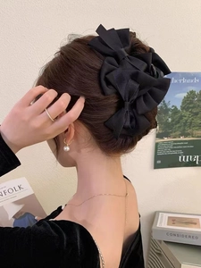 Detail of a large black satin bow hair claw clip styled on a woman's updo hairstyle