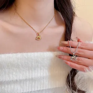Gold and silver rocking horse pendant necklaces on a white knitted sweater