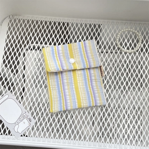 Vertical yellow and blue striped fabric sanitary pouch with button closure on mesh rack