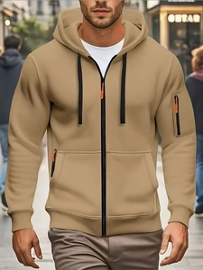 Detail of khaki men hoodie with black drawstring and orange zippers in street setting