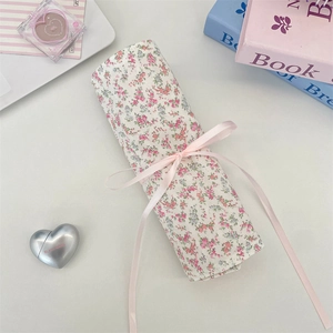 Detailed view of floral fabric makeup pouch roll with a delicate pink satin ribbon bow