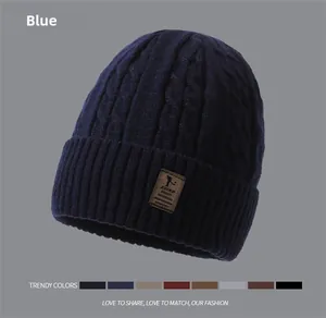 Detail view of the navy blue knit beanie with thick cable texture and leather patch logo