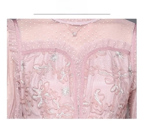 Détail d'une robe en dentelle rose avec résille à pois, broderie florale et fils argentés