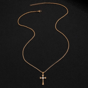 Détail macro du pendentif croix dorée avec cristal sur une fine chaîne dorée