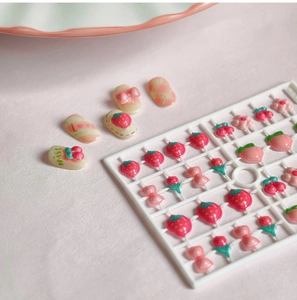 Gros plan de breloques nail art 3D en résine avec motifs fraise rose et fleurs