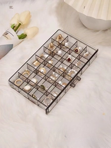 Macro view of transparent acrylic jewelry organizer drawer with multi-grid compartments