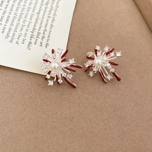 Close-up of elegant firework stud earrings with red enamel and zircon on a textured background