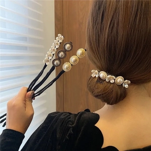 Detalle de accesorio para moño con flores y perlas en banda negra flexible para pelo