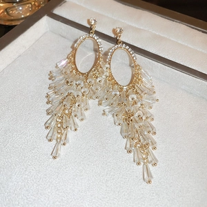 Macro shot of long golden tassel earrings with crystal beads on a beige velvet display box