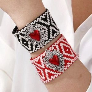 Close-up of woven ethnic bracelets with vintage silver heart pendants in red finish
