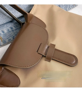 Detail of beige nylon tote bag with brown leather handles and premium stitching texture