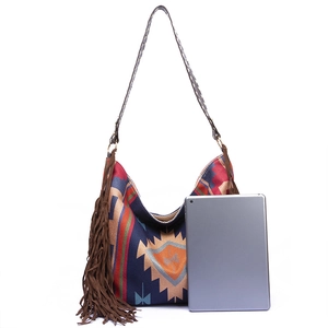 Detail of woven boho tote bag with tribal pattern, long tassels and leather shoulder strap