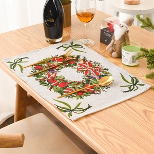 Detail of knitted Christmas placemat with holly wreath and festive golden cutlery