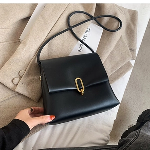 Détail du sac bandoulière en cuir noir avec fermoir en métal doré en forme de U sur blanc