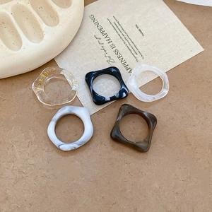 Detail of five acrylic rings in marble, amber, and gold leaf on a warm-toned background