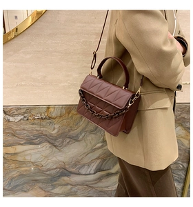 Détail d'un sac bandoulière marron foncé en cuir matelassé avec chaîne en résine