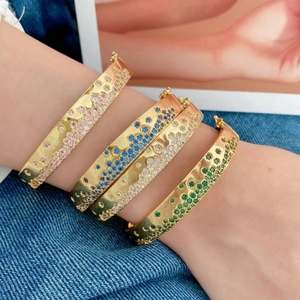 Bracelets joncs dorés ornés de zircons colorés portés ensemble sur le poignet
