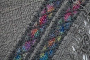 Close-up of ethnic knit shawl showing colorful woven textures and long tassels