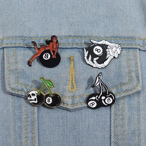 Detailansicht der 8-Ball-Emaille-Pins mit Skelett- und Mädchen-Motiv auf Jeansstoff