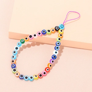 Detailed view of colorful evil eye beads and a blue smiley face on a pink phone lanyard