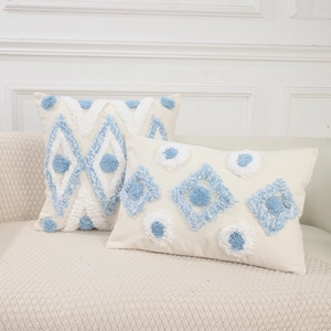 Moderne getuftete Kissenbezüge mit blau-weißen Quasten auf einem cremefarbenen Sofa