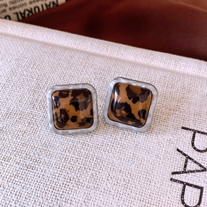 Détail macro de boucles d'oreilles carrées en acrylique léopard avec bords argentés mats