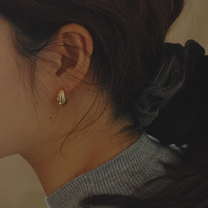 Close-up of elegant 18k gold-plated teardrop earrings on a model in soft lighting