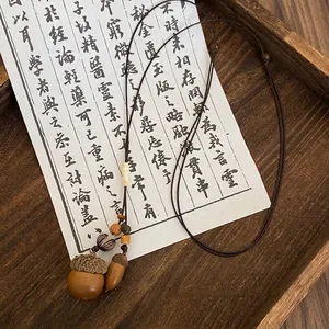 Detail of vintage acorn pendant necklace with wooden beads on a rustic wooden tray
