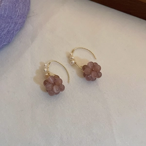 Close-up of butterfly style earrings with mauve beads, pearls, and golden hooks