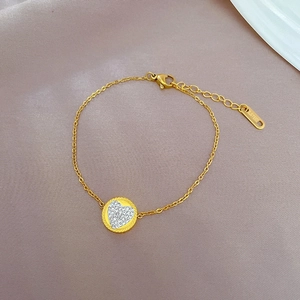 Detailed shot of gold heart chain bracelet with cubic zirconia on purple fabric