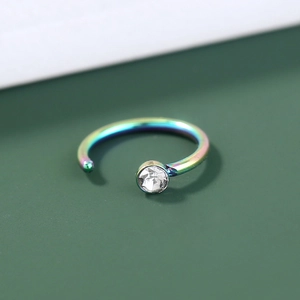 Macro shot of a rainbow stainless steel nose ring with a clear zircon stone setting
