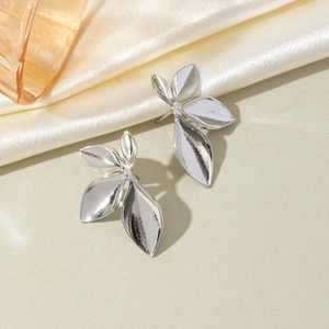 Detailed view of silver leaf stud earrings on elegant silk with amber glass accents