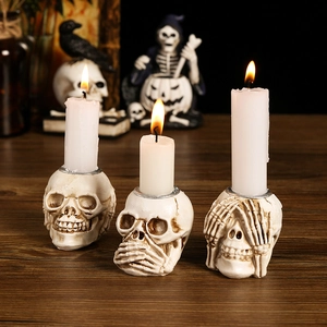 Three skeleton figurines holding candles in a festive Halloween table setting decor